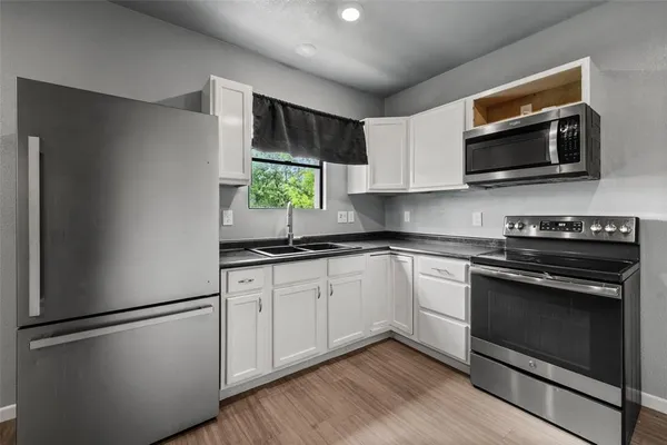 a kitchen with stainless steel appliances a stove microwave and sink
