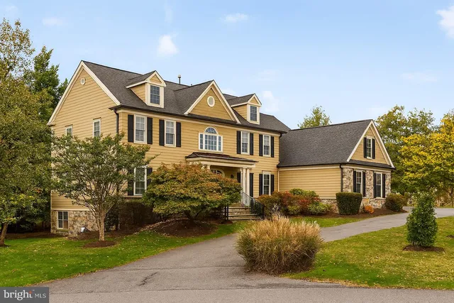 a view of a white house next to a yard with big trees