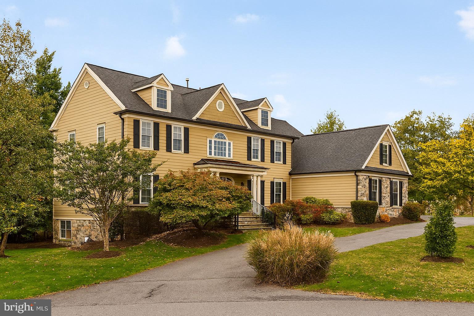 a view of a white house next to a yard with big trees