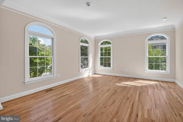 an empty room with fireplace wooden floor and windows