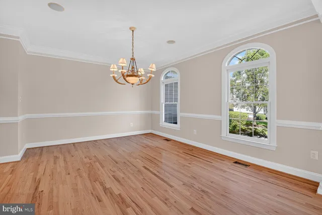 a view of an empty room with wooden floor and windows