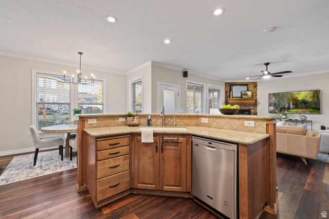 6208 West Bull River Road Highland, UT 84003 - Photo 25 of 90 Kitchen island featuring a built-in sink, stainless steel dishwasher, wood-finish cabinetry with dark hardware, stone-look countertops, and a complementary tile backsplash