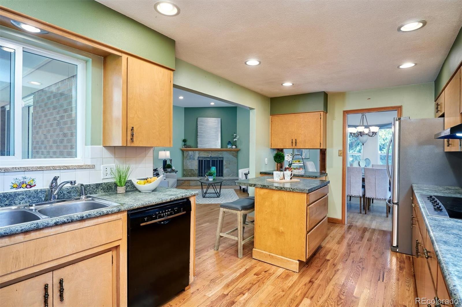 22 Rangeview Drive Wheat Ridge, CO 80215 - Photo 15 of 40 a kitchen with a stove top oven a sink dishwasher a dining table and chairs with wooden floor