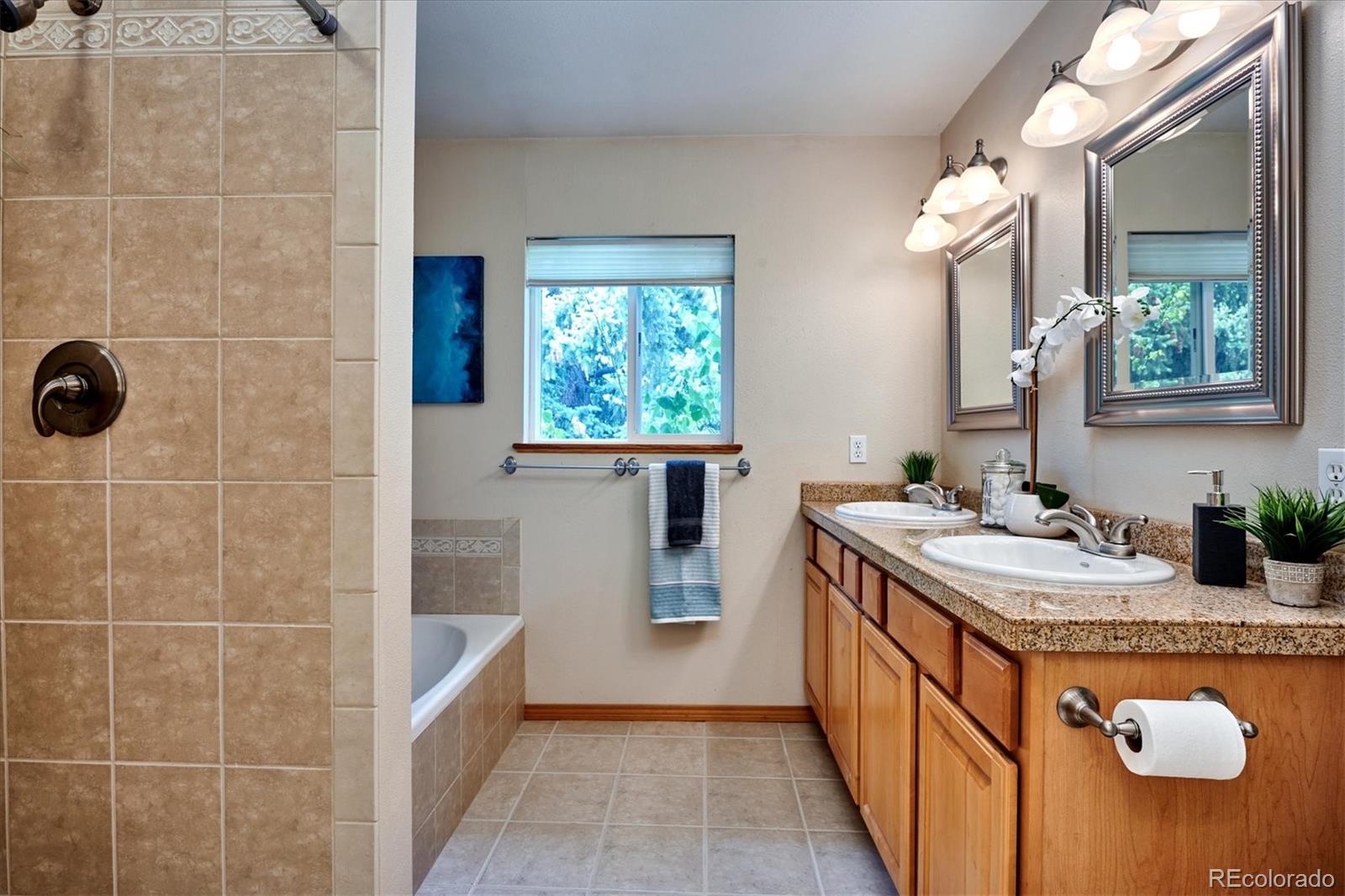22 Rangeview Drive Wheat Ridge, CO 80215 - Photo 22 of 40 a bathroom with a granite countertop sink a toilet a mirror and shower