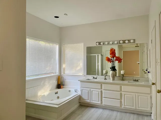 a bathroom with a double vanity sink mirror and bathtub