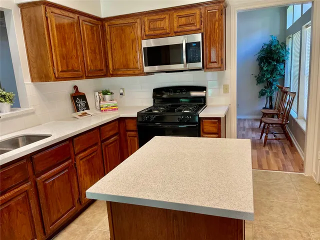 a kitchen with stainless steel appliances a stove a refrigerator a sink and wooden cabinets