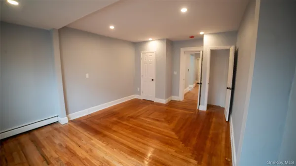 a view of an empty room with wooden floor and cabinet