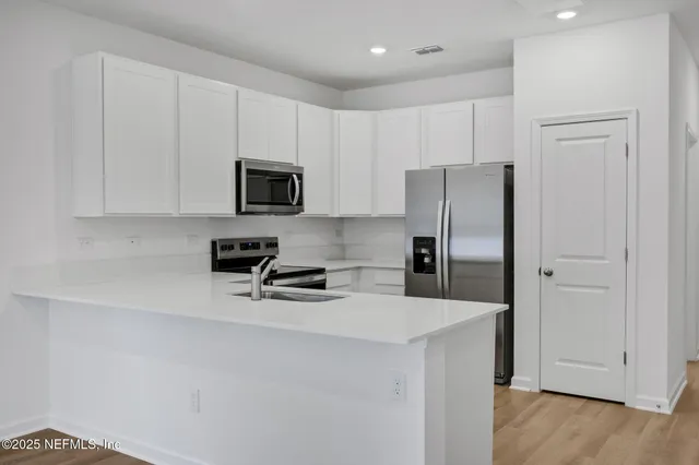 a kitchen with stainless steel appliances a refrigerator a stove a microwave and cabinets