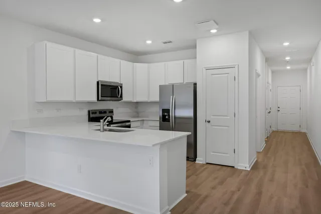 a kitchen with a refrigerator a stove top oven a sink and cabinets