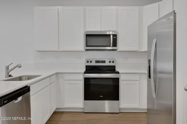 a kitchen with white cabinets stainless steel appliances and a sink