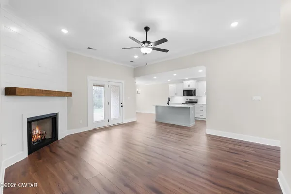 a view of an empty room with wooden floor fireplace and a window