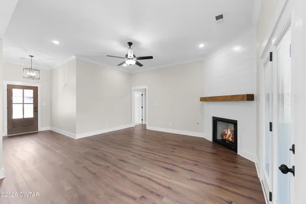 a view of an empty room with wooden floor and a fireplace