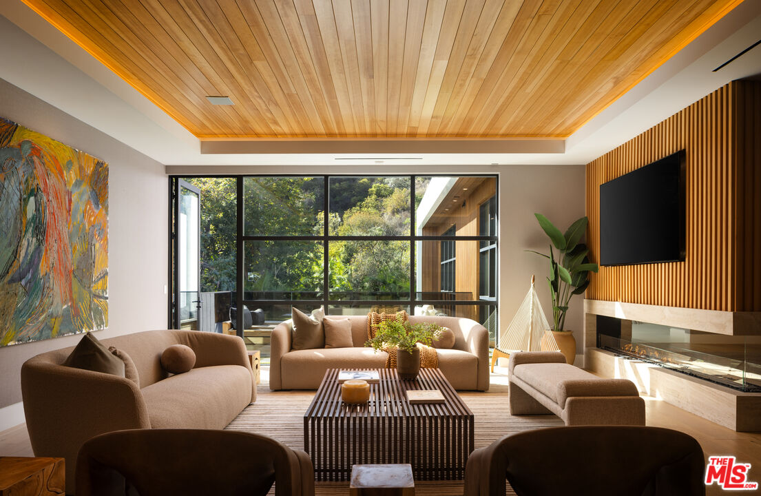 13187 Chalon Road Los Angeles, CA 90049 - Photo 16 of 39 a living room with furniture a flat screen tv and a floor to ceiling window