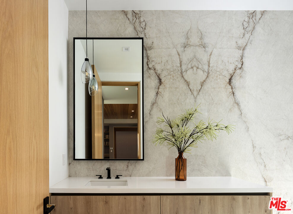 13187 Chalon Road Los Angeles, CA 90049 - Photo 24 of 39 a bathroom with a granite countertop sink a mirror and shower
