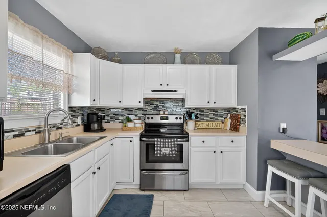 a kitchen with stainless steel appliances granite countertop white cabinets and a stove top oven
