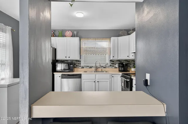 a kitchen with a refrigerator and white cabinets