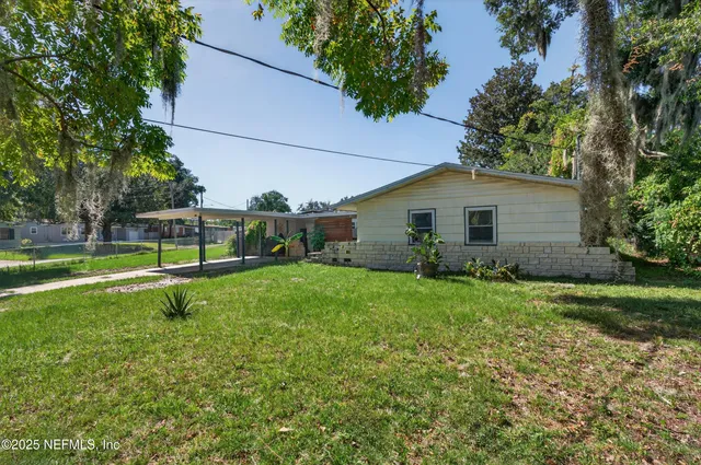 a view of a house with backyard and a tree