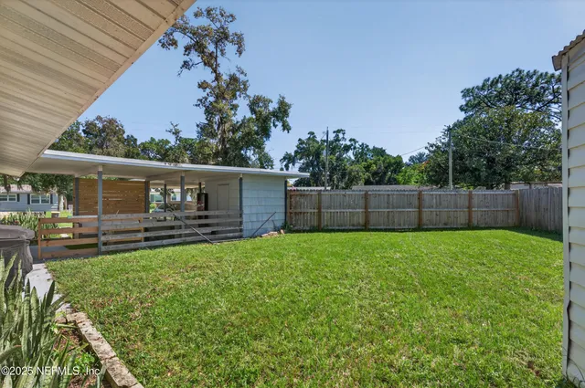 a view of a backyard with table and chairs and wooden fence