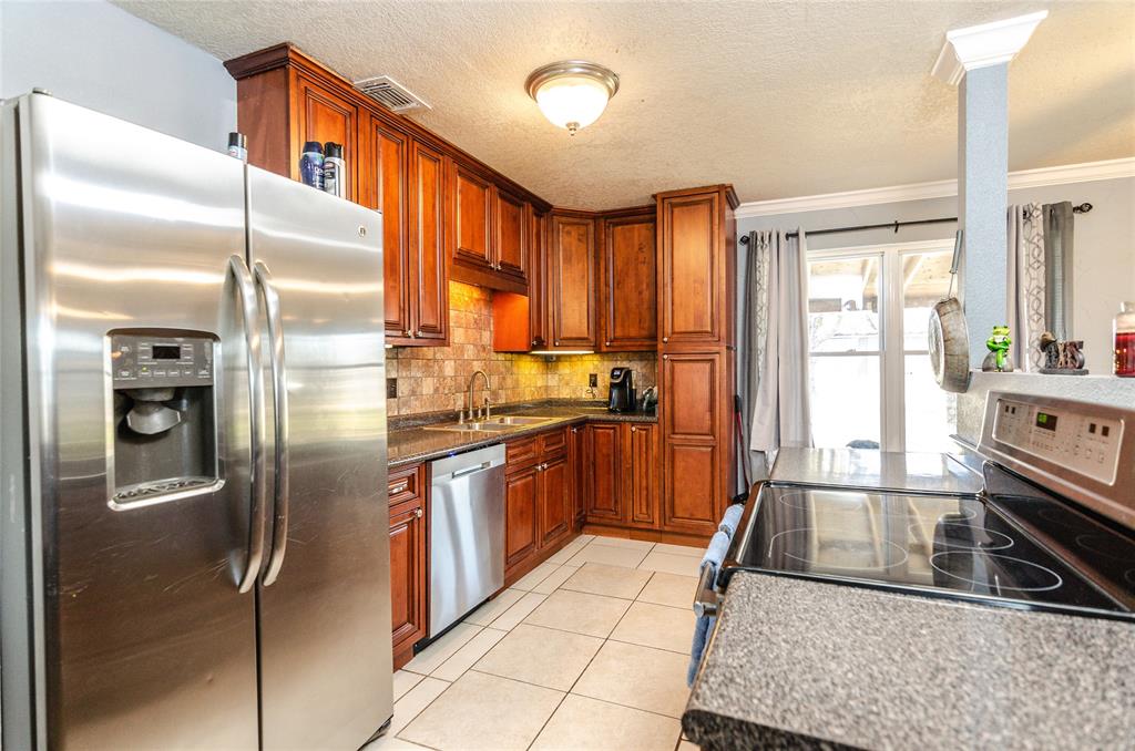 a kitchen with stainless steel appliances granite countertop a refrigerator a stove and a sink with large window