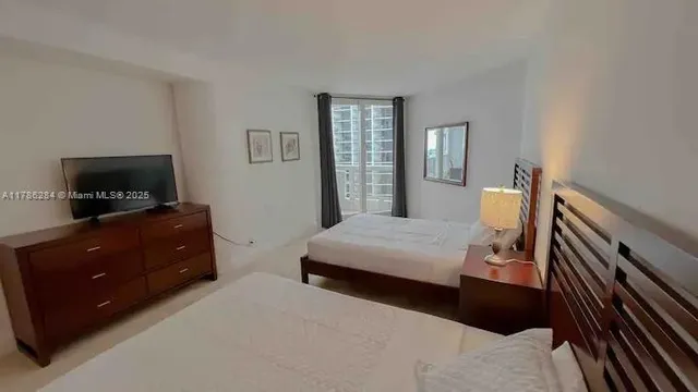 a bedroom with a bed and a flat tv screen on dresser