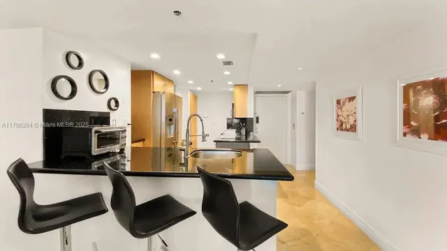 a kitchen with stainless steel appliances kitchen island granite countertop a sink and a refrigerator