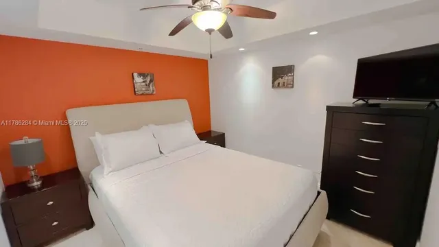 a bedroom with a bed and a flat tv screen on dresser