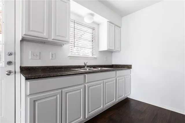 a kitchen with granite countertop white cabinets and a sink