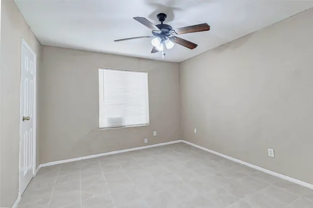 an empty room with a window and a fan