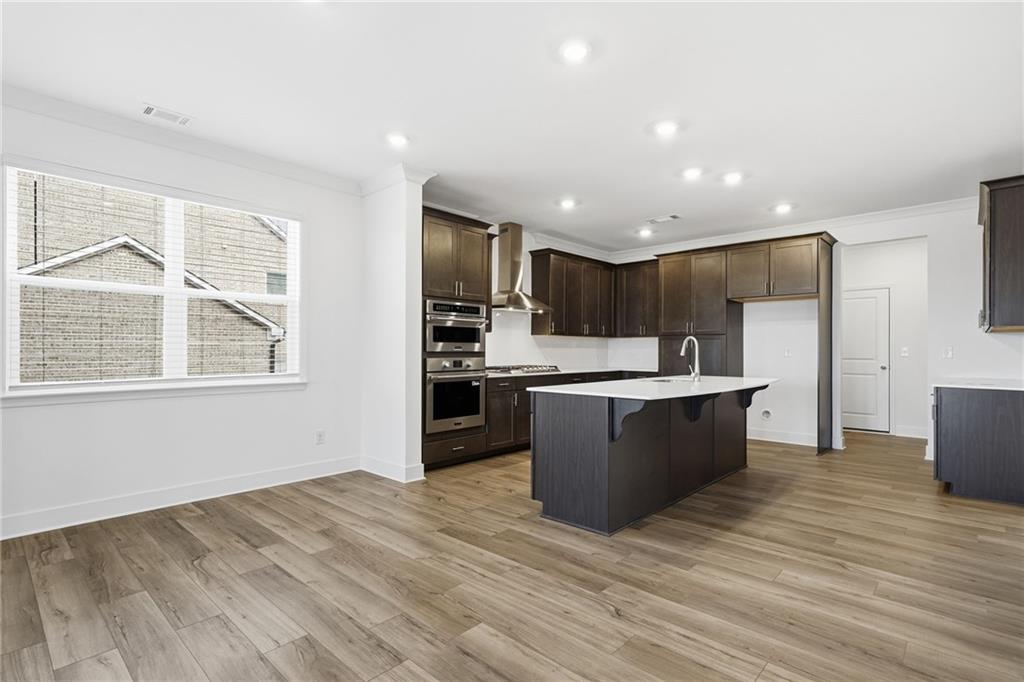 259 Deer Valley Run Canton, GA 30115 - Photo 5 of 25 a large kitchen with kitchen island a sink wooden floor and stainless steel appliances