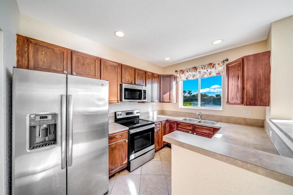 3141 Laurel Ridge Circle Riviera Beach, FL 33404 - Photo 3 of 28 a kitchen with stainless steel appliances granite countertop a refrigerator a stove and a sink with wooden floor