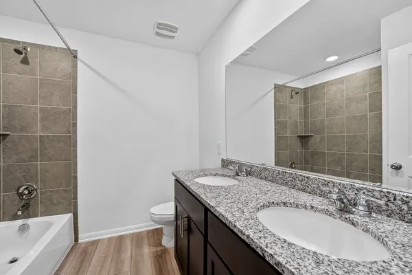 a bathroom with a granite countertop sink a toilet and shower