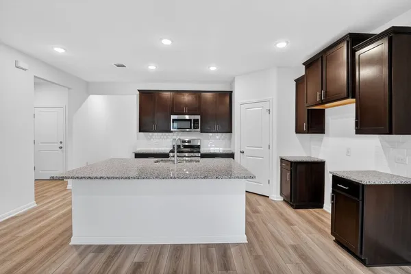 a large kitchen with stainless steel appliances kitchen island granite countertop a stove a sink a refrigerator and blue cabinets with wooden floor