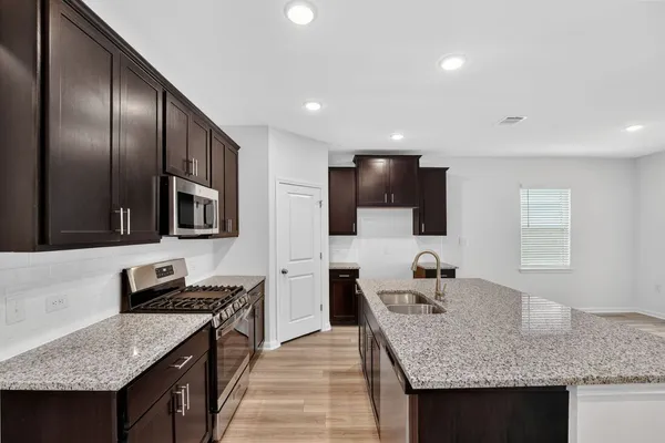a kitchen with granite countertop stainless steel appliances a sink stove top oven and cabinets
