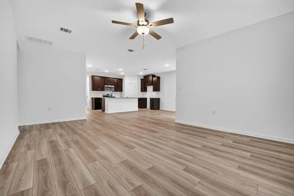 a view of empty room with wooden floor and ceiling fan