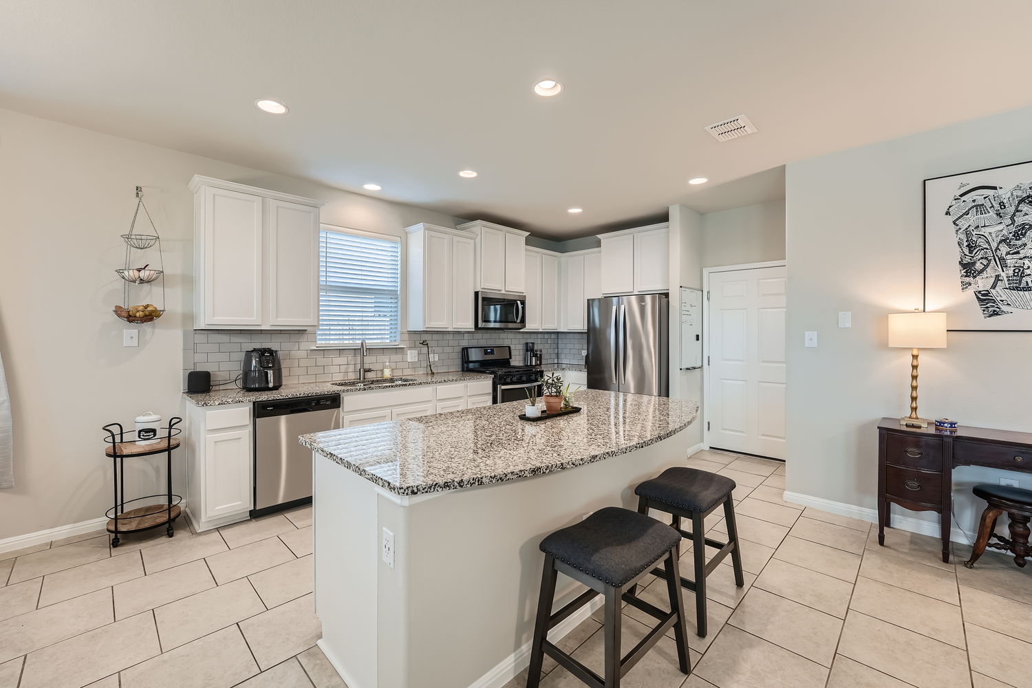 1205 Falconer Way, Unit 91 Austin, TX 78748 - Photo 13 of 39 Kitchen featuring stainless steel appliances, white cabinetry, light stone countertops, a kitchen bar, and light tile patterned floors