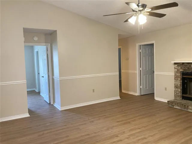 an empty room with wooden floor a ceiling fan and staircase