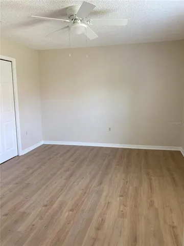 an empty room with wooden floor and fan