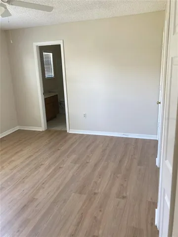 an empty room with wooden floor closet and windows