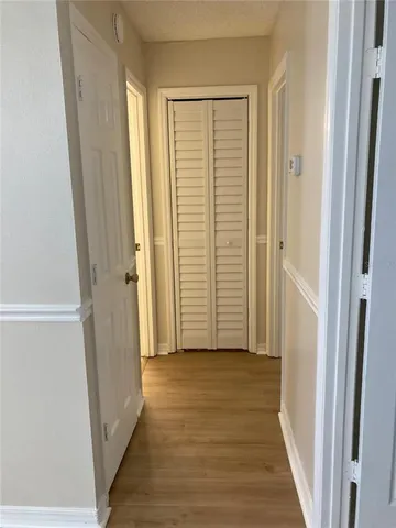 a view of a hallway with wooden floor and closet area