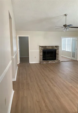 an empty room with wooden floor fireplace and windows