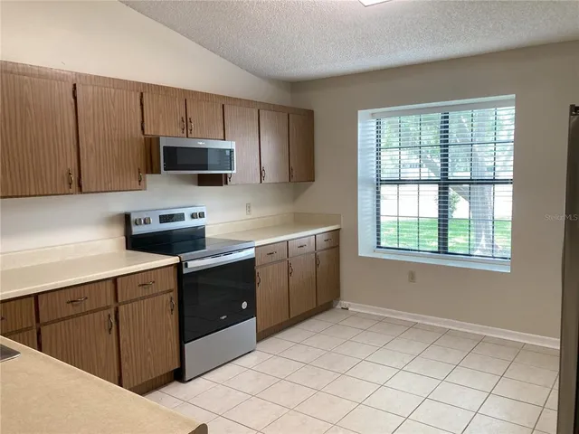 a kitchen with stainless steel appliances a sink a stove a microwave and wooden cabinets