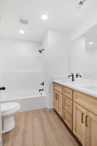 a spacious bathroom with double vanity a toilet a bathtub and shower
