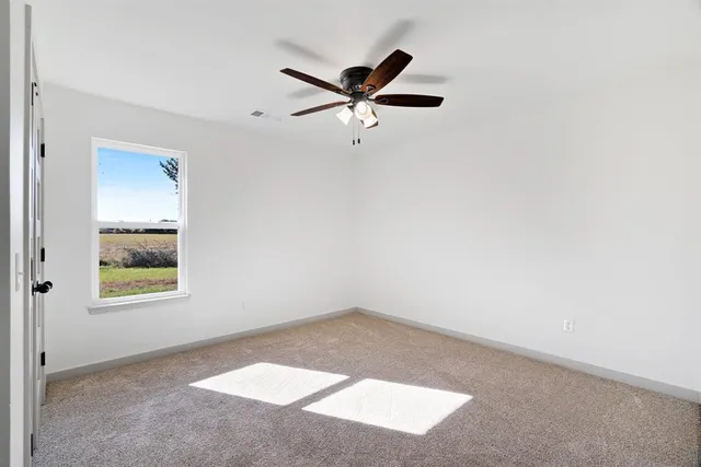 an empty room with a window and a ceiling fan