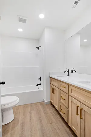a spacious bathroom with double vanity a toilet a bathtub and shower