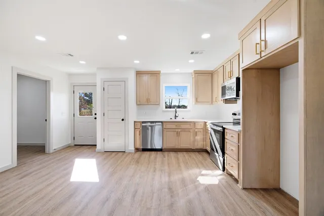 a large kitchen with a lot of counter space wooden floor and stainless steel appliances