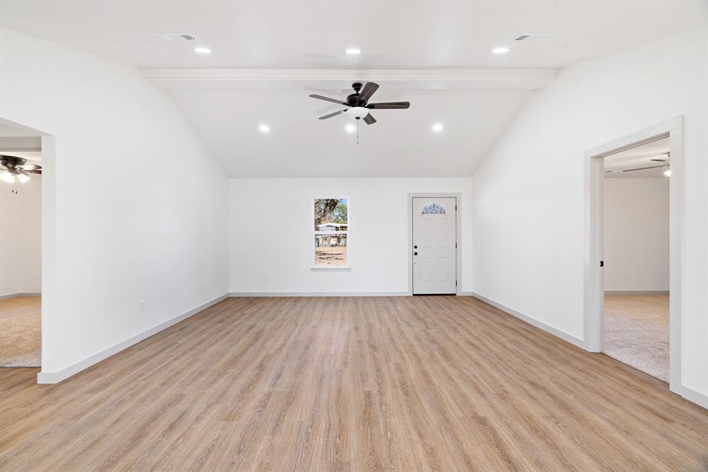 728 County Road Powderly, TX 75473 - Photo 8 of 19 an empty room with wooden floor a ceiling fan ceiling fan and windows