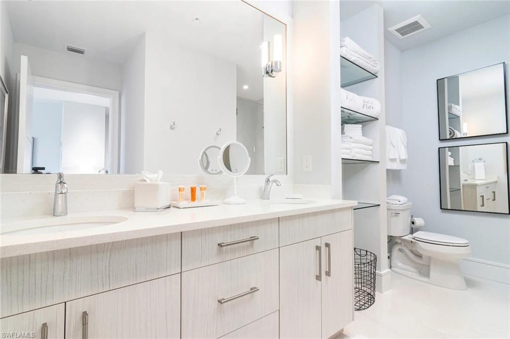 101 8th Street South, Unit 206 Naples, FL 34102 - Photo 7 of 15 a bathroom with double sink a toilet and a mirror