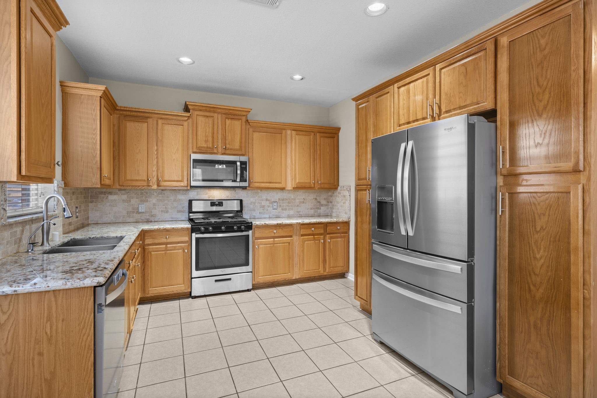 19327 Dickson Park Drive Spring, TX 77373 - Photo 10 of 43 Gourmet chefs and home cooks alike will love this spacious kitchen, featuring tile flooring, a sunny window for light, warm cabinetry with crown molding and concealed hinges, recessed lighting, sleek granite countertops, and stainless steel appliances. Plenty of room to create, gather, and enjoy!