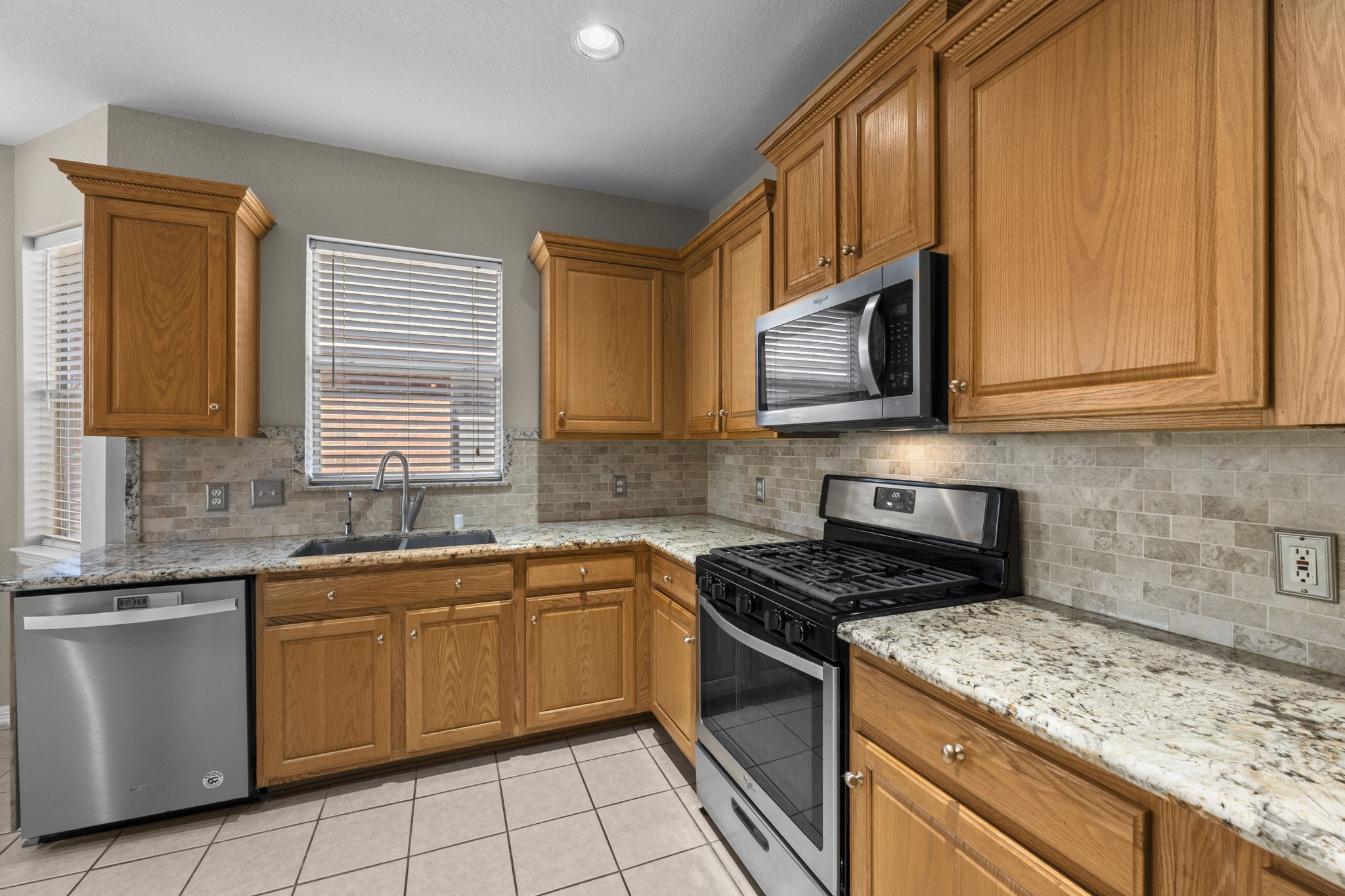 19327 Dickson Park Drive Spring, TX 77373 - Photo 11 of 43 A pristine showcase of elegance and function, this extraordinary kitchen features Whirlpool stainless steel appliances, including a 5-burner gas range with oven, dishwasher, microwave, and a French door refrigerator with two drawers. The stainless sink with a pull-out sprayer and filtered water dispenser adds both charm and practicality — a true chef’s kitchen designed for everyday living and grand gatherings alike.