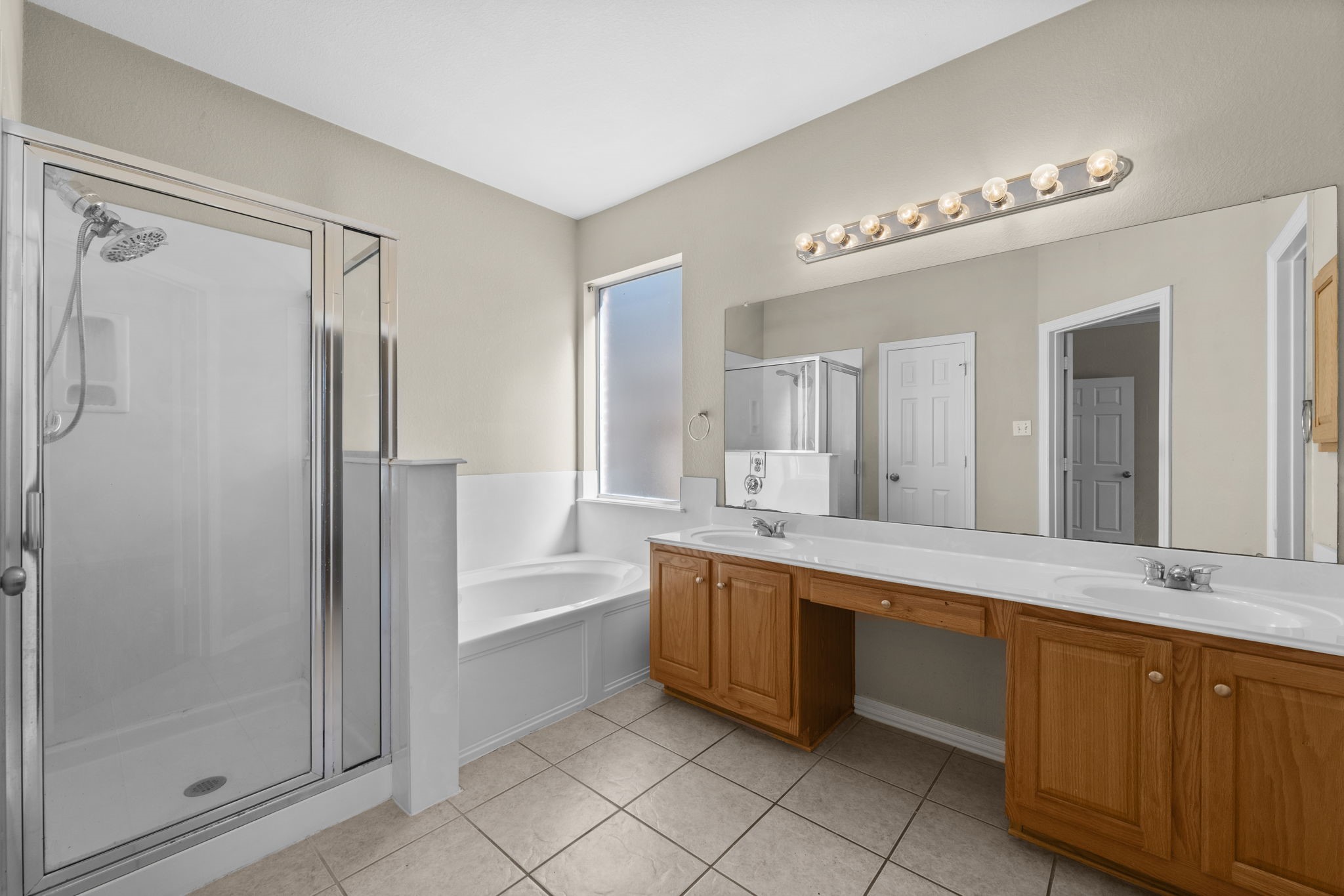 19327 Dickson Park Drive Spring, TX 77373 - Photo 18 of 43 Truly a retreat for getting ready on a busy morning or stealing away for an evening out, your en-suite bath features elegant double door entry, tile flooring, dual vanities, jetted tub, shower, window with rain glass for privacy, medicine cabinet, private commode, and huge walk-in closet.